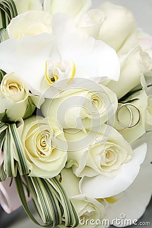 Beautiful wedding bouquet of roses and orchids and two gold and platinum wedding rings Stock Photo