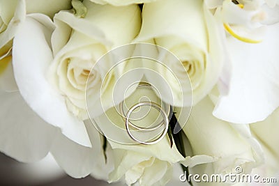 Beautiful wedding bouquet of roses and orchids and two gold and platinum wedding rings Stock Photo