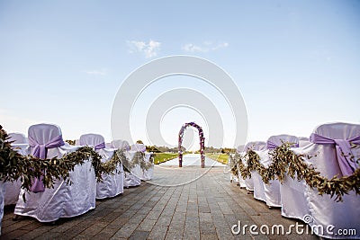 Beautiful wedding. The round arch is decorated with flowers and greenery, the ceremony on the seashore. Guest chairs are decorated Stock Photo