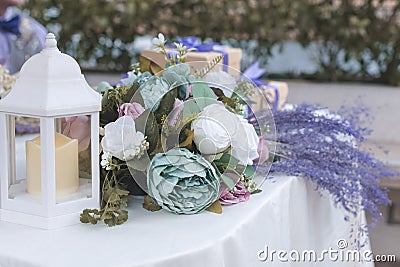 Beautiful wedding tabletop decoration. With sage green, blush, lavender and white colored roses and white candle lantern Stock Photo