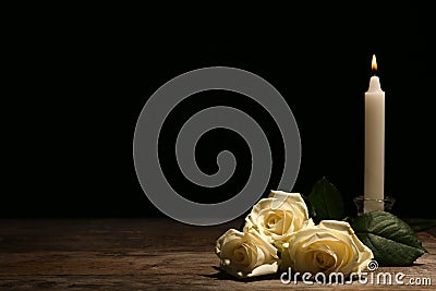 Beautiful white roses and candle on table against black background Stock Photo