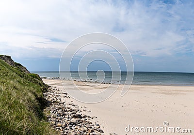 Beautiful white sand beach with high grassy sand dunes behind Stock Photo