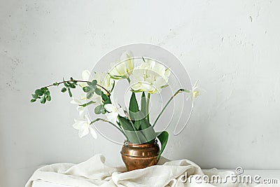 Beautiful white tulips and daffodils on wooden table against rustic wall. Happy Mothers day. Stylish simple spring bouquet in Stock Photo