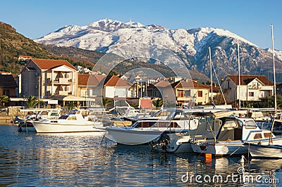 Beautiful winter Mediterranean landscape. Fishing boats in harbor on background of snowy mountain peaks. Montenegro, Tivat city Stock Photo