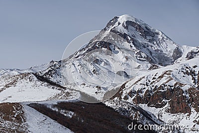 Beautiful winter mountains landscape on the sunrise. High snow covered mountains in the clouds. Georgia, Kazbegi. Stock Photo