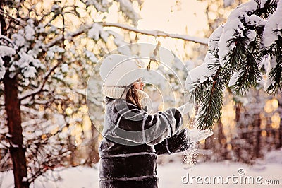 Beautiful winter portrait of child girl in sunny winter forest plays with snowy fir branch Stock Photo