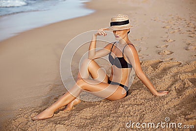 Beautiful Woman apply sun protection cream on her smooth tanned legs. Skin care. Legs on the beach. Portrait of female smearing mo Stock Photo