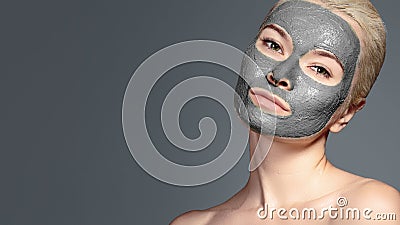 Beautiful Woman Applying Black Facial Mask. Beauty Treatments. Spa Girl Apply Clay Facial mask on grey background Stock Photo