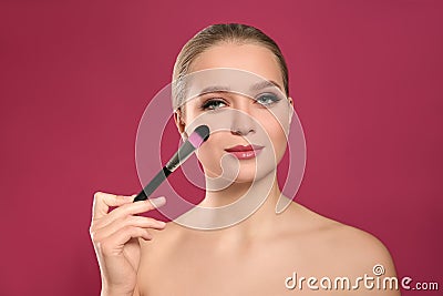 Beautiful woman applying makeup with brush on background Stock Photo