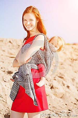 Beautiful woman with a baby in a sling. Mom and baby. Mother and Stock Photo