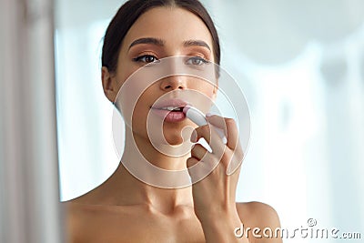 Beautiful Woman With Beauty Face Applies Balm On Lips. Skin Care Stock Photo