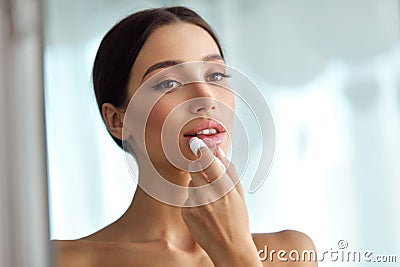 Beautiful Woman With Beauty Face Applies Balm On Lips. Skin Care Stock Photo