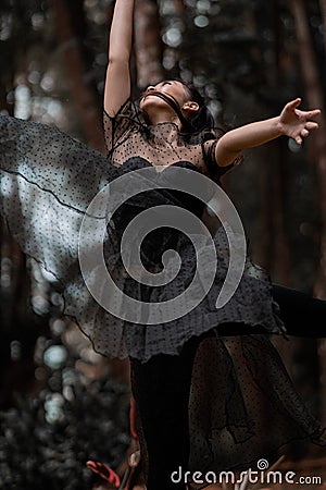 Beautiful women with black ballet costumes flying in the air like reaching something in the sky Stock Photo