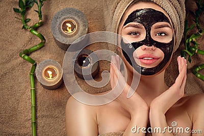 Beautiful woman with black purifying black charcoal mask on her face. Beauty model girl with black facial peel-off mask Stock Photo