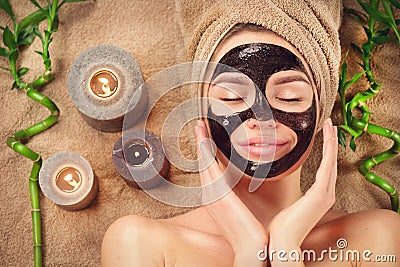 Beautiful woman with black purifying black mask on her face. Beauty model girl with black facial peel-off mask lying in spa salon Stock Photo