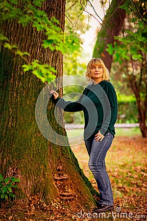 Beautiful woman,blonde,walking in the Park in autumn,in jeans and a green jumper. Stock Photo