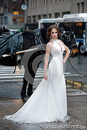 Beautiful woman bride in long white wedding dress posing in New York City street Stock Photo