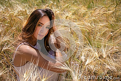 Beautiful woman, bride with blue eyes and brown hair walks through corn field on a sunny summer`s day Stock Photo