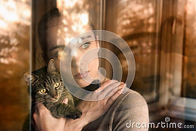 Beautiful woman with a cat and sits by the window Stock Photo