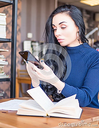 Beautiful woman at coffee shop. Person side view, send message by smartphone. Student reading books for exam in library Stock Photo