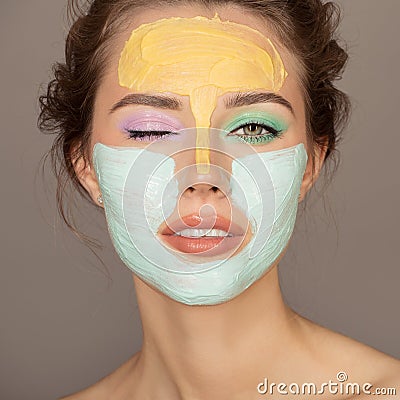 beautiful woman with colorful cream mask on her face Stock Photo