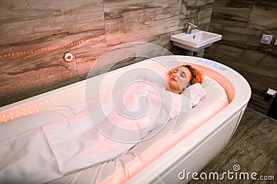 Beautiful woman, covered with special hot blanket lying on the spa bed, having hot spa treatment Stock Photo