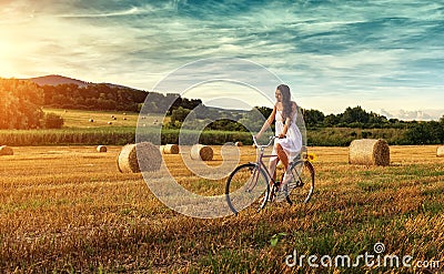 Beautiful woman cycling on an old red bike, in a wheat field Stock Photo