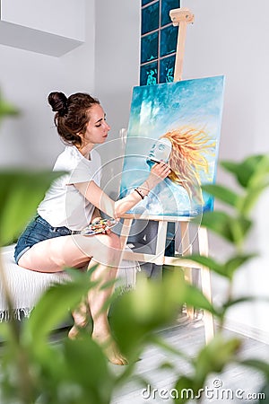 Beautiful woman draws paintbrush, enjoying picture, inspired drawing picture, girls with orange hair. Home workshop Stock Photo