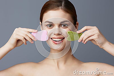 beautiful woman facial scraper skin care posing Gray background Stock Photo
