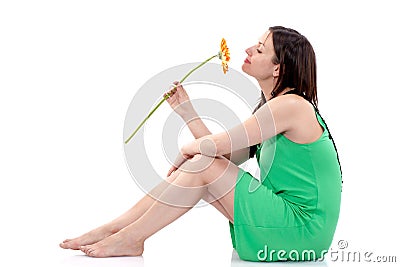 Beautiful woman in green dress sitting on the floor with gerbera on white background Stock Photo