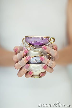 Beautiful woman hands with perfect pink nail polish holding little vintage tea cups Stock Photo