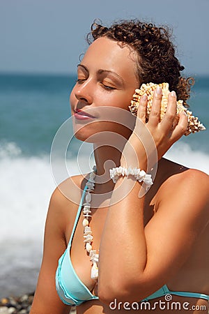 Beautiful woman has leant seashell bowl to an ear Stock Photo
