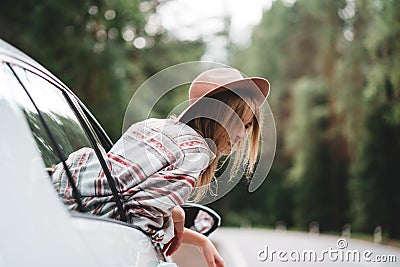 Beautiful woman in hat enjoying view of the road from the car window Stock Photo