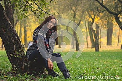 Beautiful woman having rest under tree. Lonely woman enjoying nature landscape in autumn. Stock Photo