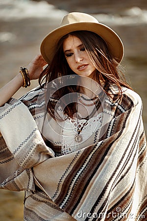 Beautiful woman hipster portrait, holding hat and poncho, stylish outfit, boho travel concept, sensual look Stock Photo