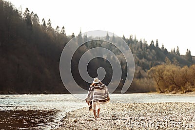 Beautiful woman hipster walking on river beach in mountains, wear Stock Photo
