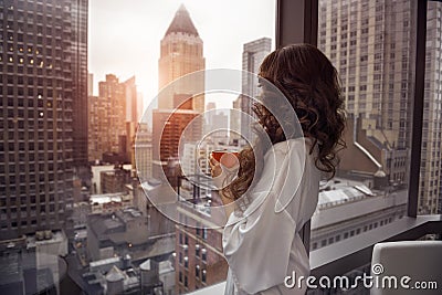 Beautiful woman holding coffee cup and looking to the window in luxury Manhattan penthouse apartments Stock Photo