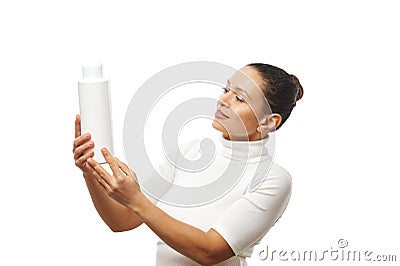 Beautiful woman holding a white container with a beauty product, looking at it and examining it. Isolated on a white background Stock Photo