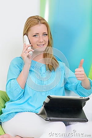 Beautiful woman at home with tablet shows thumb up Stock Photo