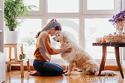 beautiful woman hugging her adorable golden retriever dog at home. love for animals concept. lifestyle indoors Stock Photo