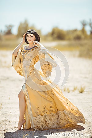 Beautiful woman like Egyptian Queen Cleopatra on in desert outdoor. Stock Photo
