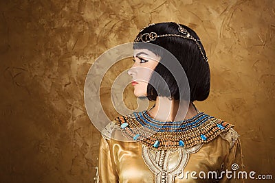Beautiful woman like Egyptian Queen Cleopatra on golden background. Side view, face profile Stock Photo