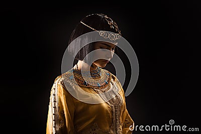 Beautiful woman like Egyptian Queen Cleopatra with sad face on black background Stock Photo