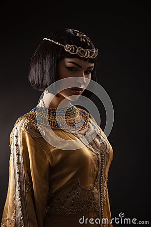 Beautiful woman like Egyptian Queen Cleopatra with serius face on black background. Stock Photo