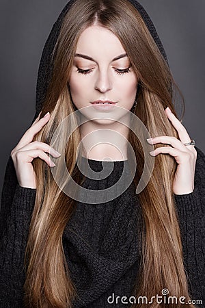 Beautiful woman with long, gorgeous dark blond hair. She is dressed in warm gray knit dress with a hood. Stock Photo