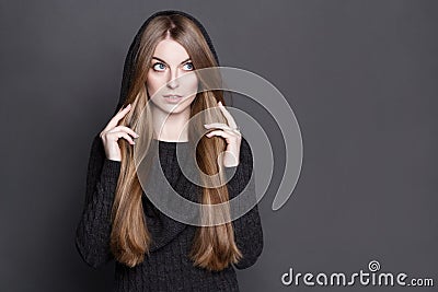 Beautiful woman with long, gorgeous dark blond hair. She is dressed in warm gray knit dress with a hood. Stock Photo