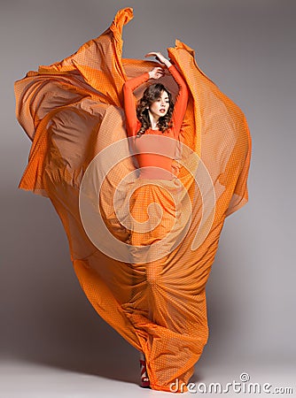 Beautiful woman in long orange dress posing dramatic Stock Photo