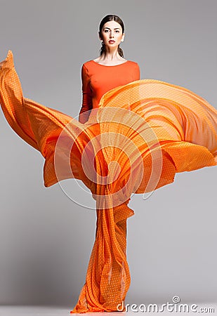 Beautiful woman in long orange dress posing dramatic Stock Photo