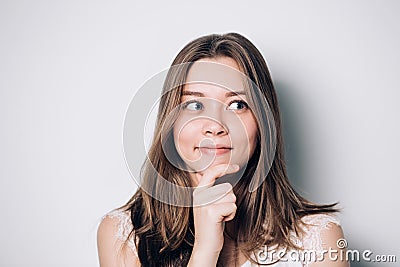 Beautiful woman looking aside holding hand under chin indenting to realize tricky plan. Stock Photo