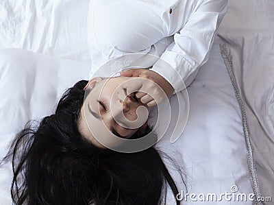 Beautiful woman lying in bed. Sexy black haired lady posing with her finger in mouth. Female enjoying, biting finger. Feeling Stock Photo